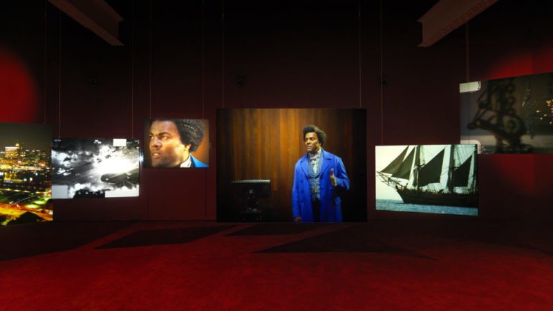 Multi-screen images of actor portraying Frederick Douglass in a dark exhibition space. 