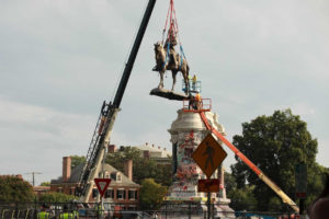 Large statue hoisted in air by large crane.