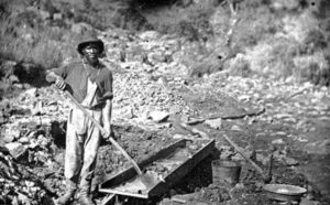 African American man standing over gold mining claim in California.
