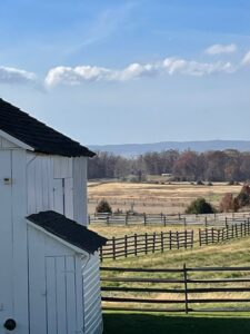 White clapboard house with a field and fence in background.